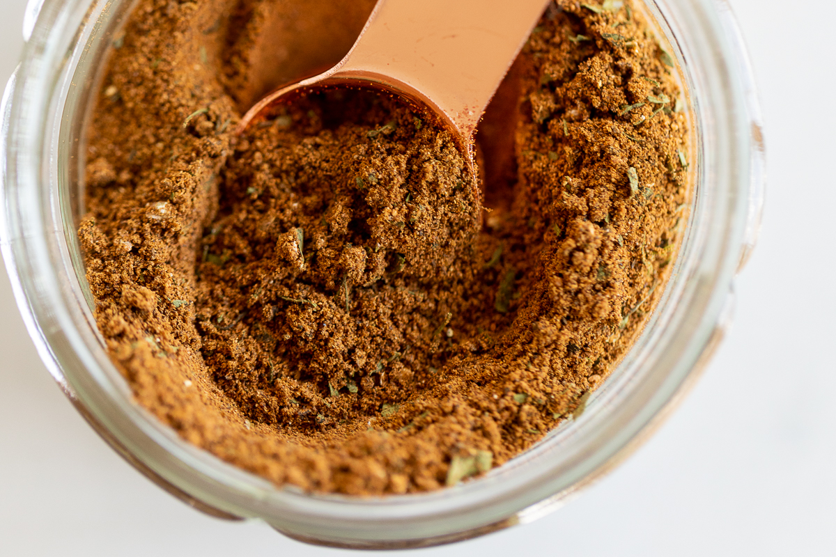 Closeup of baharat seven spice in measuring spoon set in jar