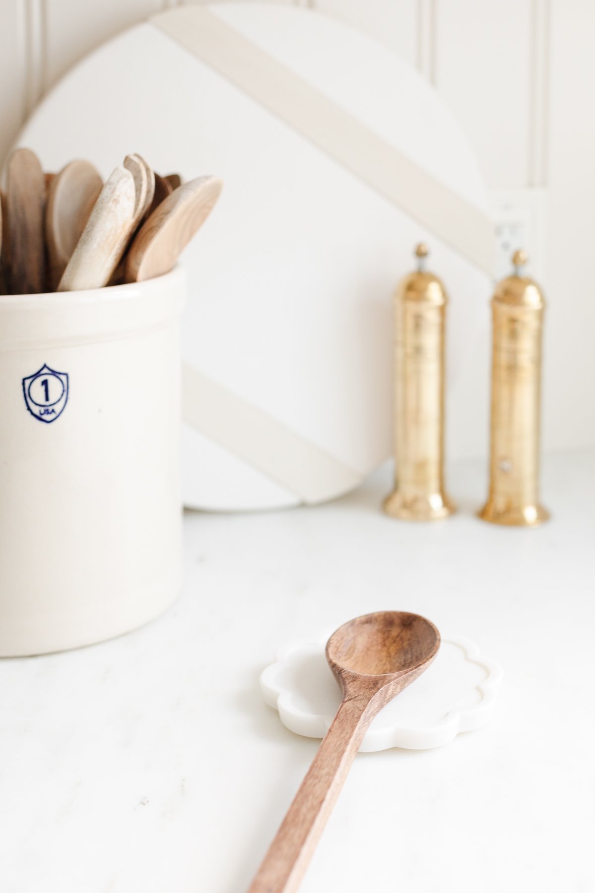 Wooden spoon resting on white marble spoon rest set on countertop