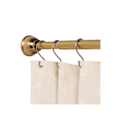 A brass shower curtain rod with a beige curtain hanging from it.