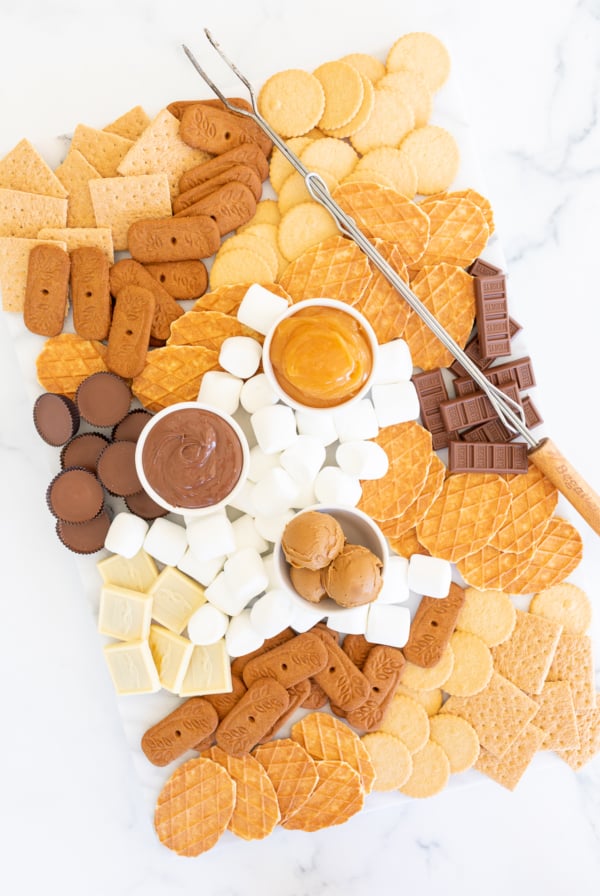 A s'mores charcuterie board filled with various marshmallows, cookies, crackers and dessert spreads.