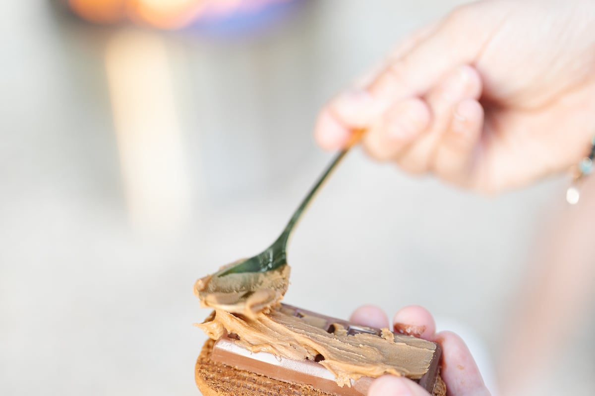 A hand spreading nutella onto a s'more.