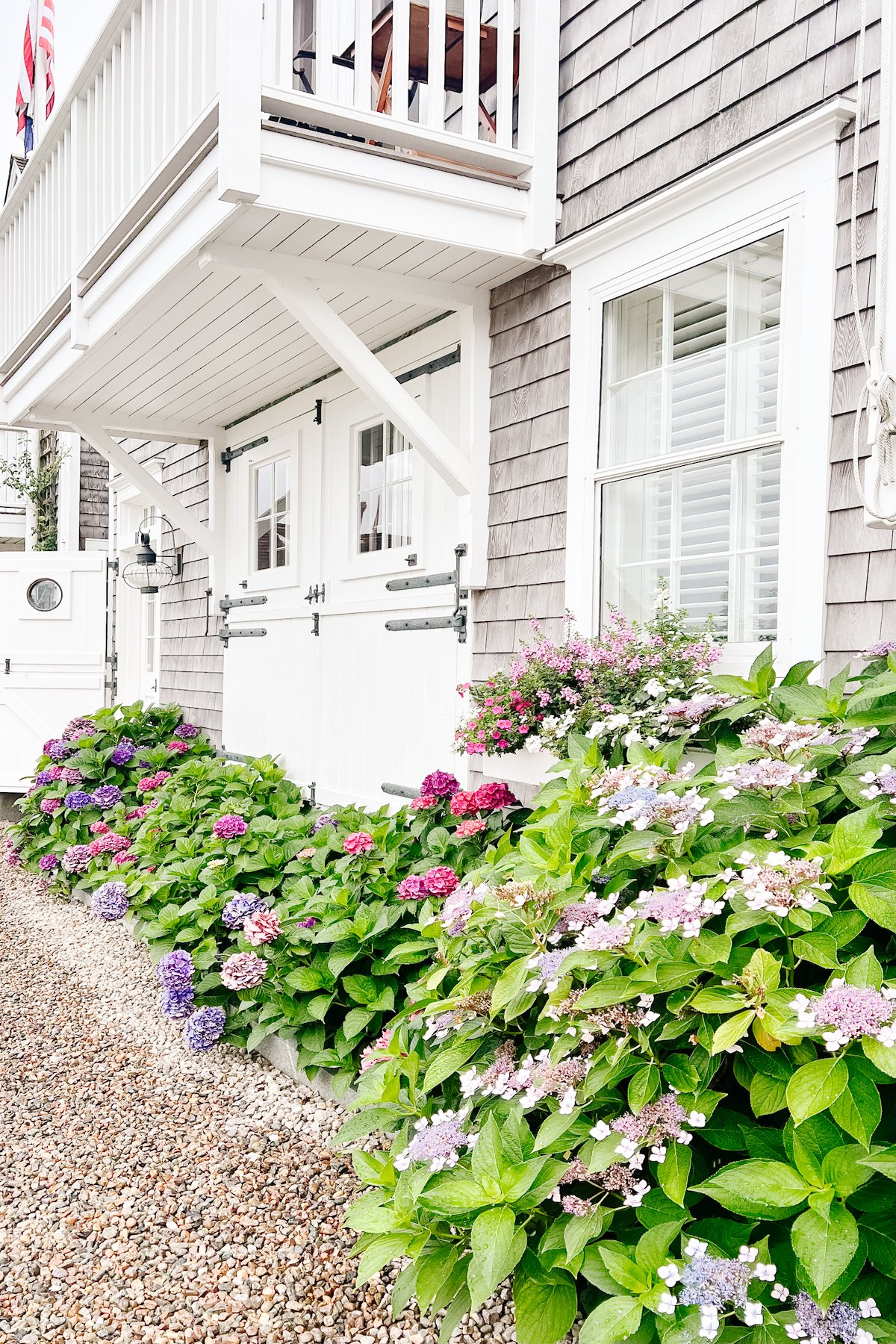 A gray shingled Nantucket house with a white carriage garage door.