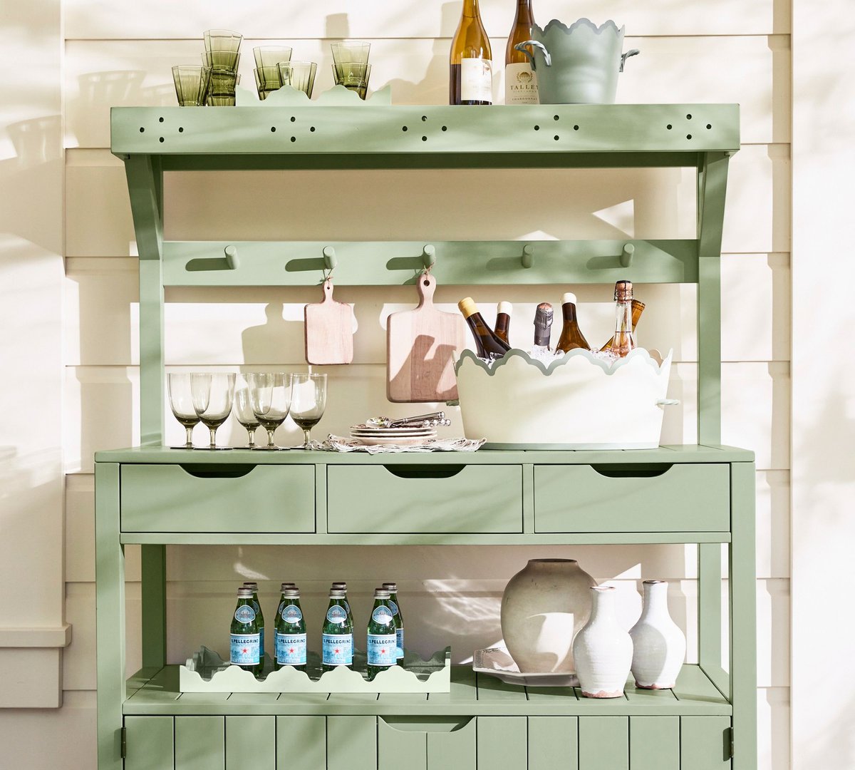 A green garden bench set up as a bar, from Julia Berolzheimer for Pottery Barn