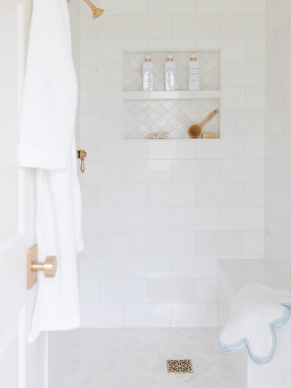 white marble shower with brass fixtures