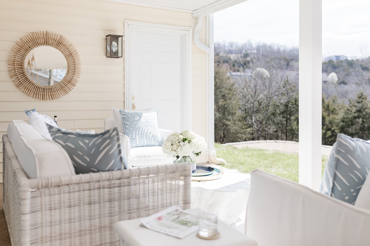 An outdoor patio decorated with white furniture and blue and white outdoor fabric pillows