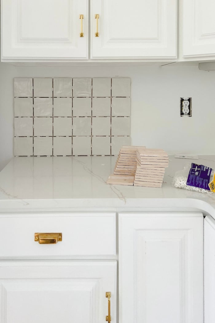 Square stacked backsplash being installed in a white kitchen.