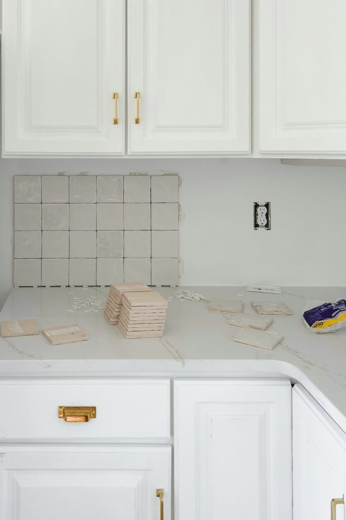 Square stacked backsplash being installed in a white kitchen.