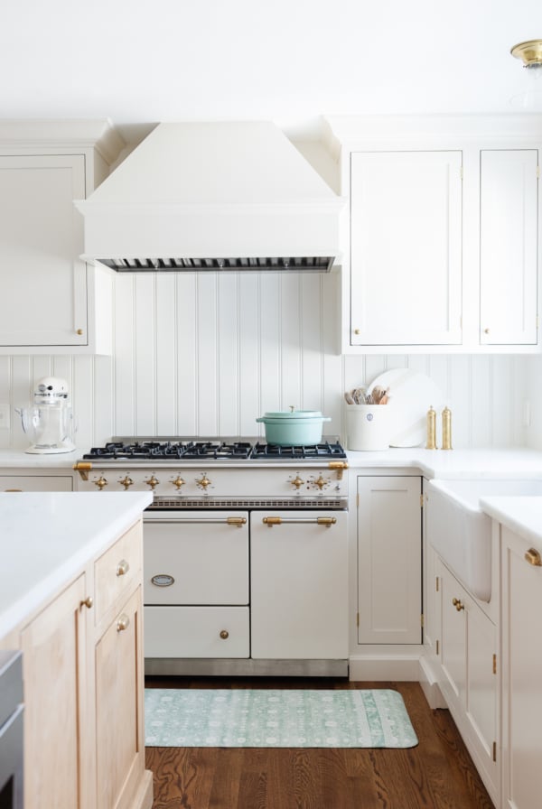 A kitchen with white cabinets and a blue anti fatigue kitchen mat.