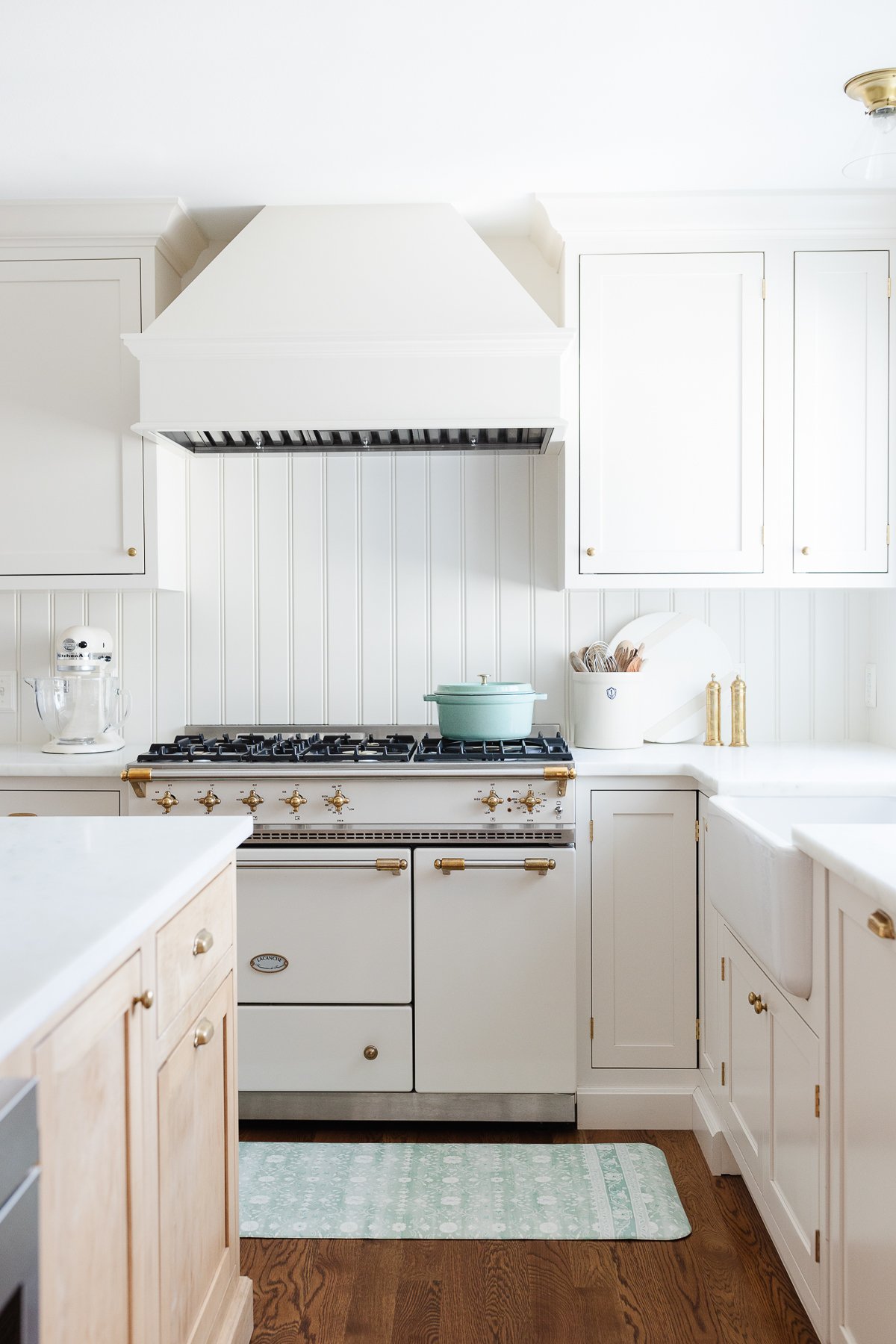 A kitchen with white cabinets and a blue anti fatigue kitchen mat.