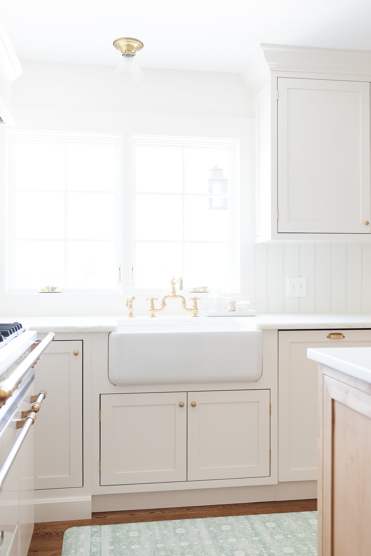 A kitchen with white cabinets and a green anti fatigue kitchen mat.