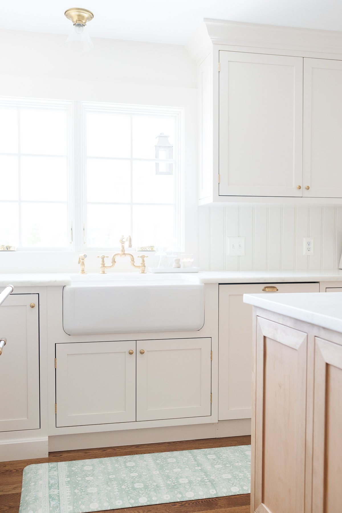 A kitchen with white cabinets and a blue anti fatigue kitchen mat.