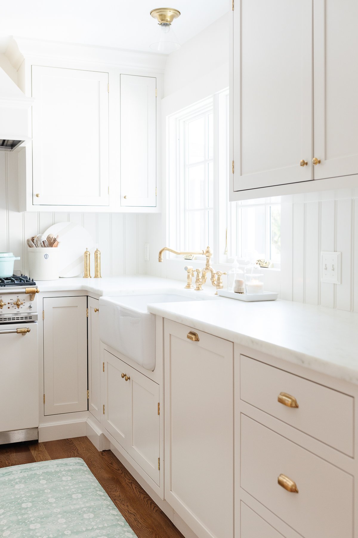 A kitchen with white cabinets and a green anti fatigue kitchen mat.