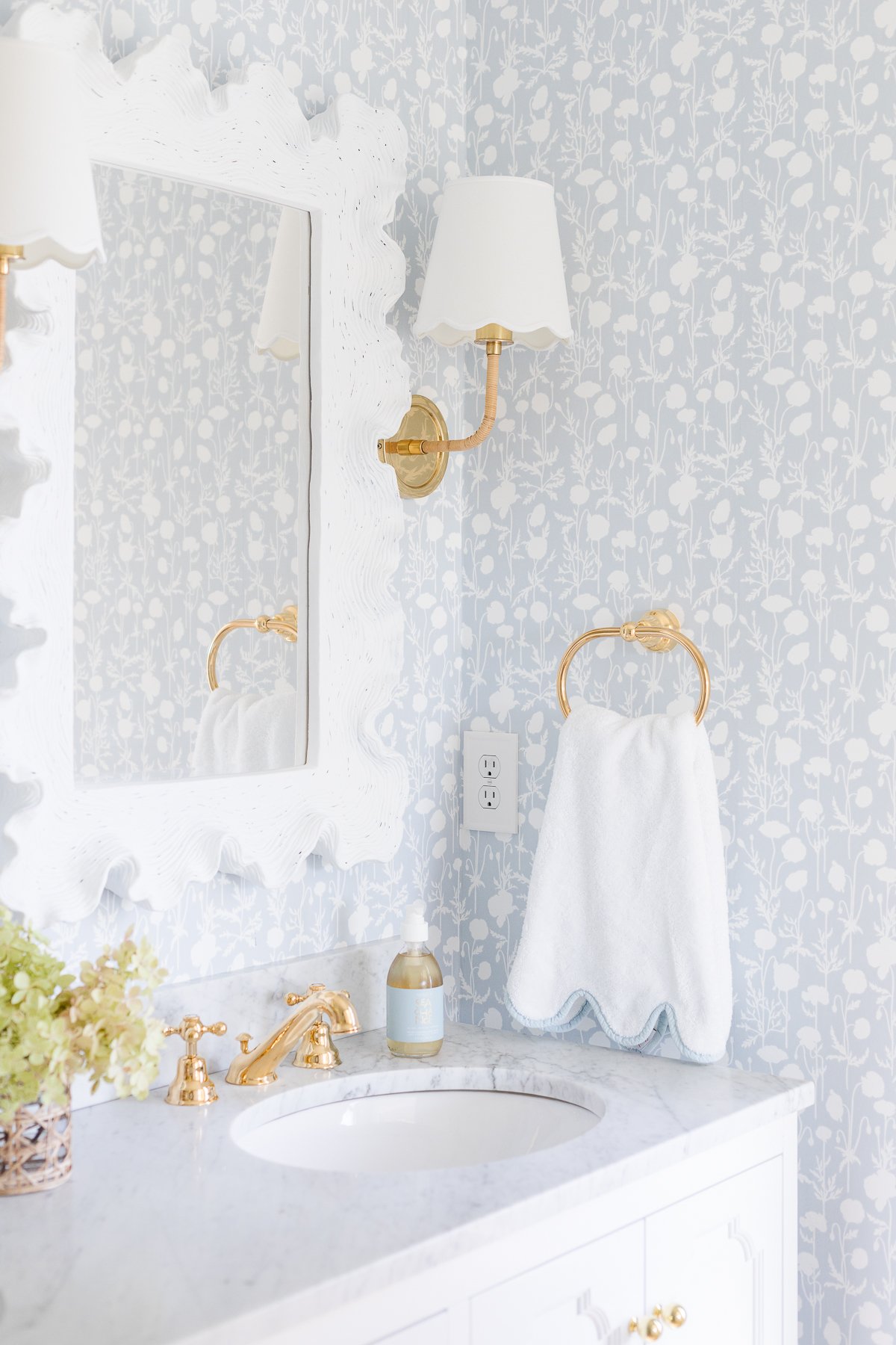 A soft blue and white wallpapered bathroom with a double white bathroom vanity.