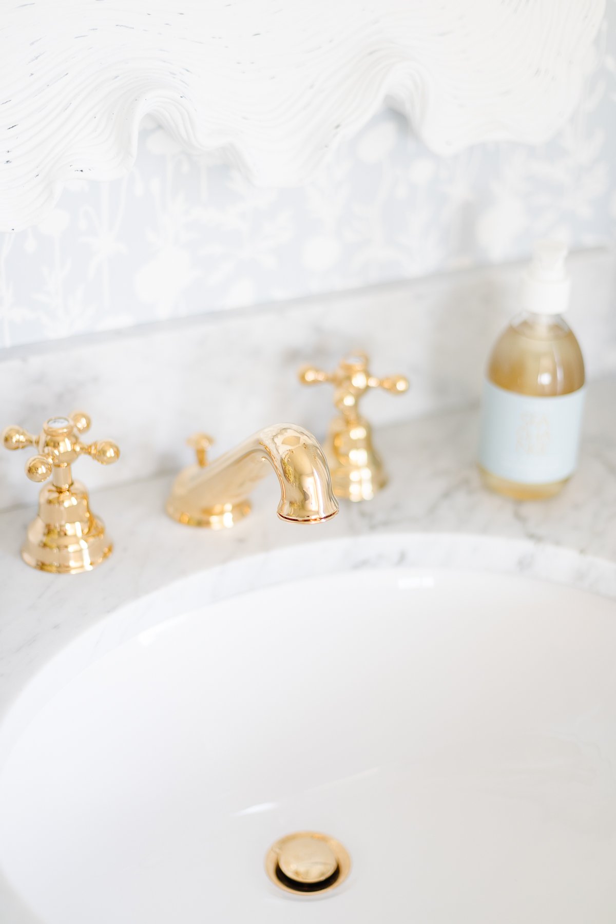 A white sink on a stock bathroom vanity with brass faucet