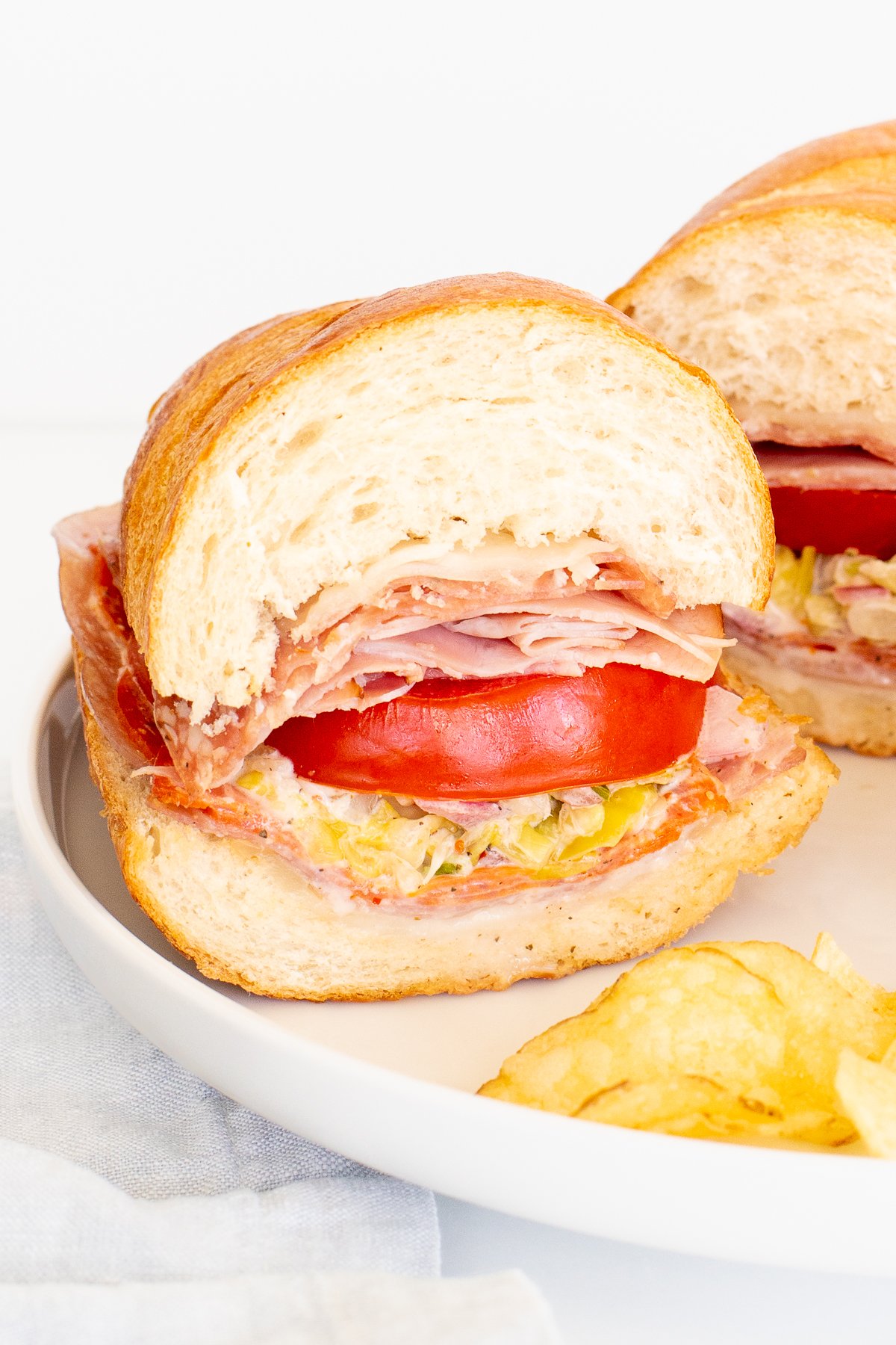 An Italian grinder sandwich, sliced in half on a white plate.