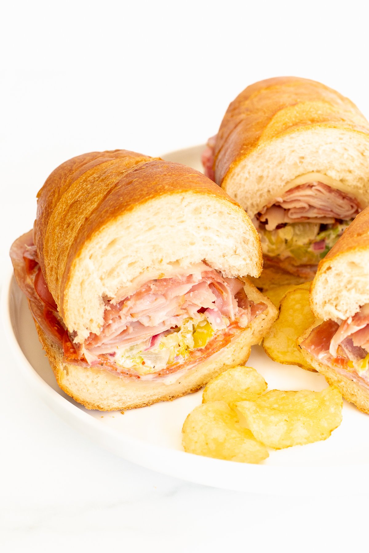 Three grinder sandwiches on a white plate.