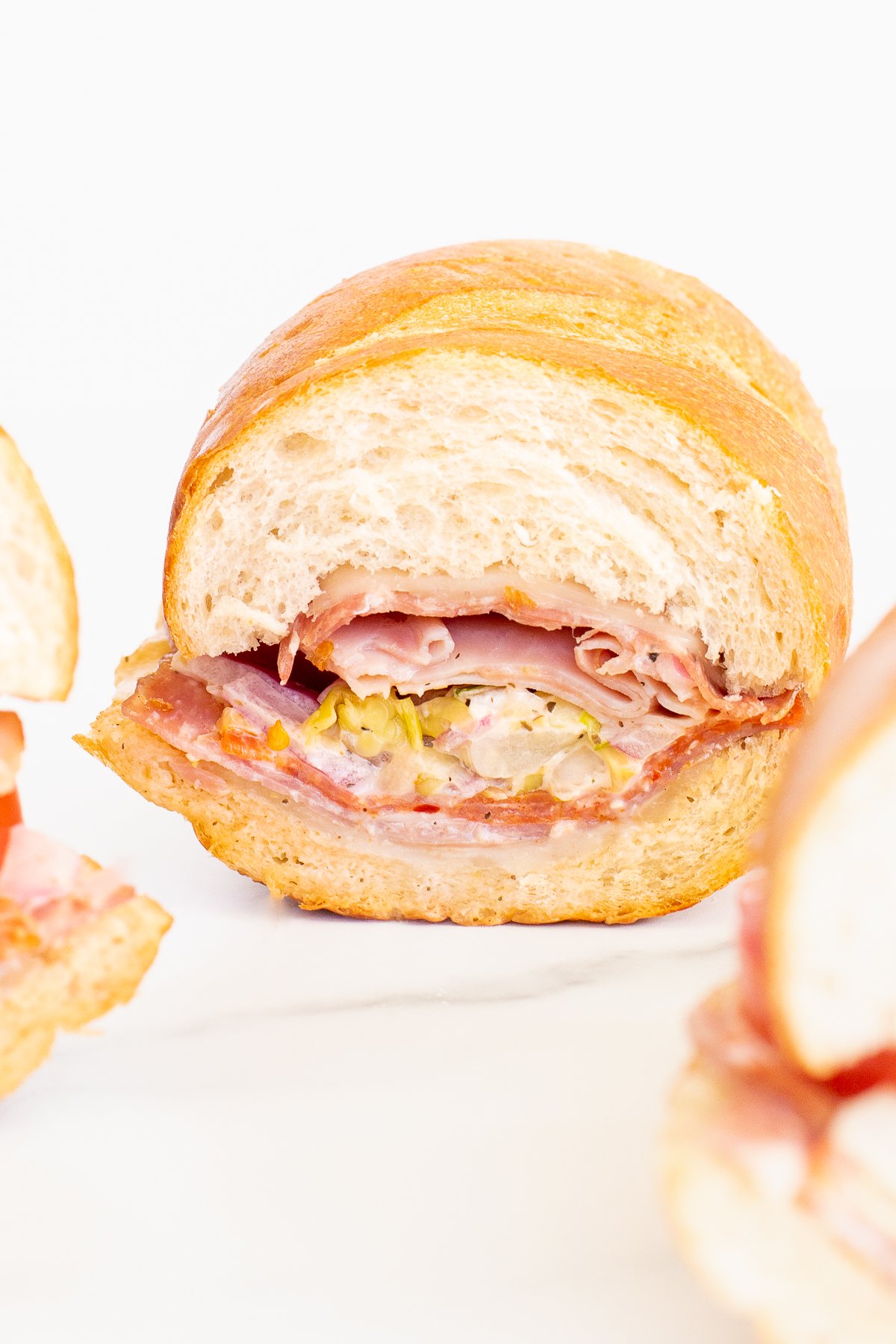 An Italian grinder sandwich, sliced in half on a white plate.