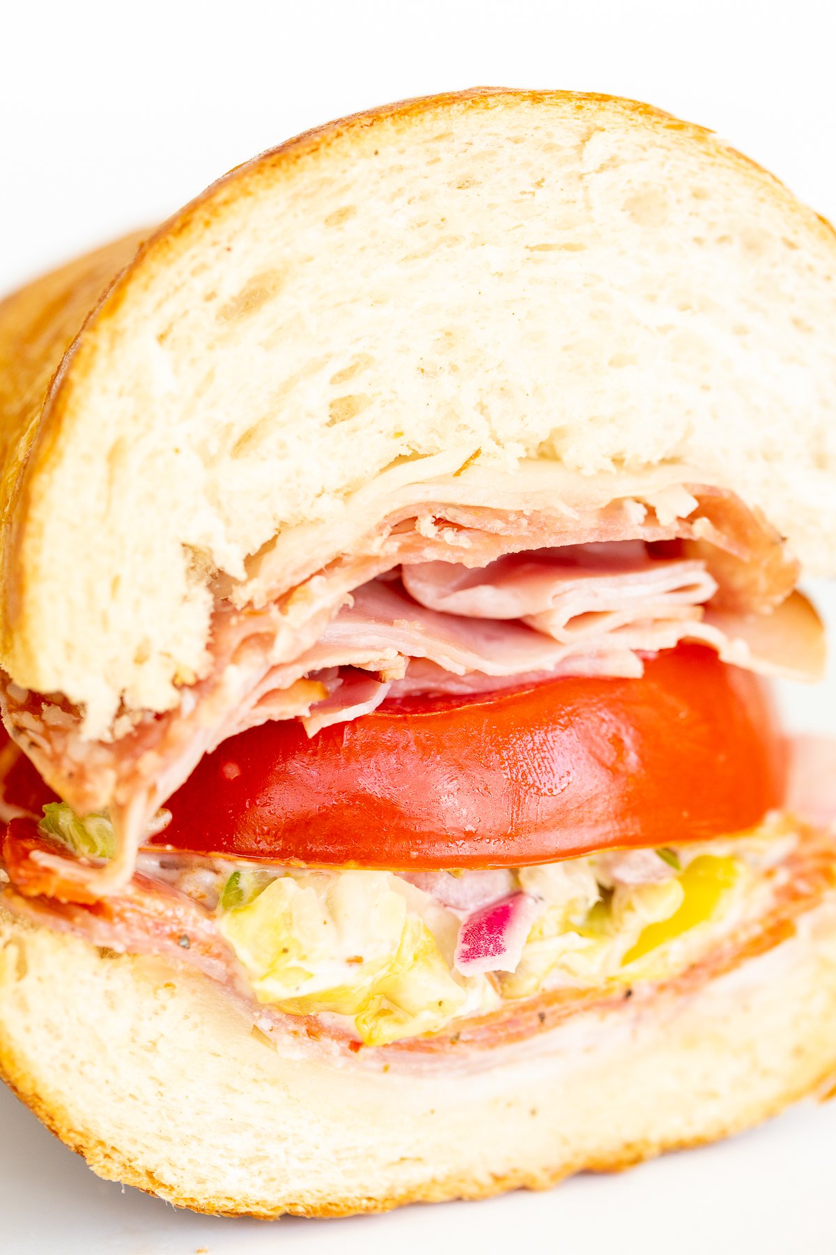An Italian grinder sandwich, sliced in half on a white plate.