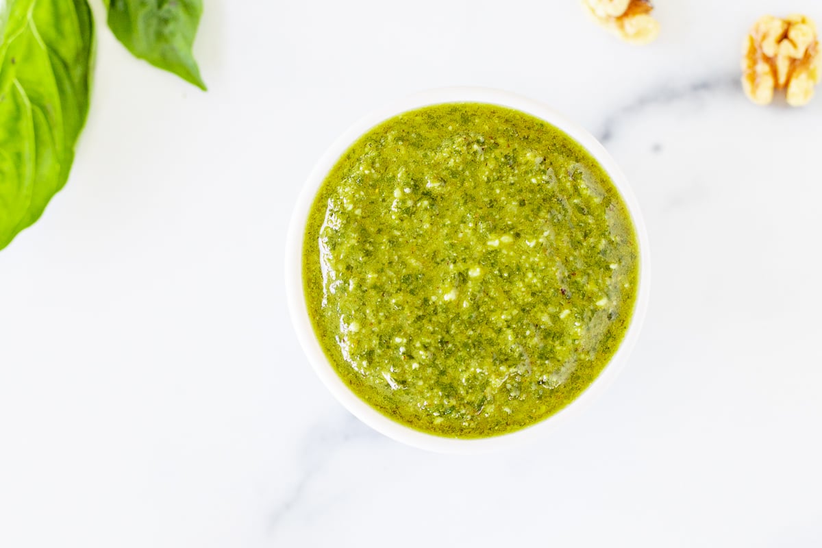 Walnut pesto in a white bowl on a marble countertop.