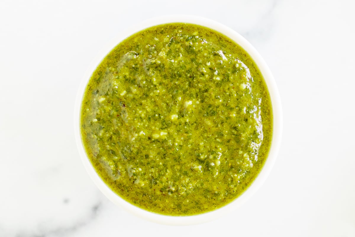 Walnut pesto in a white bowl on a marble countertop.