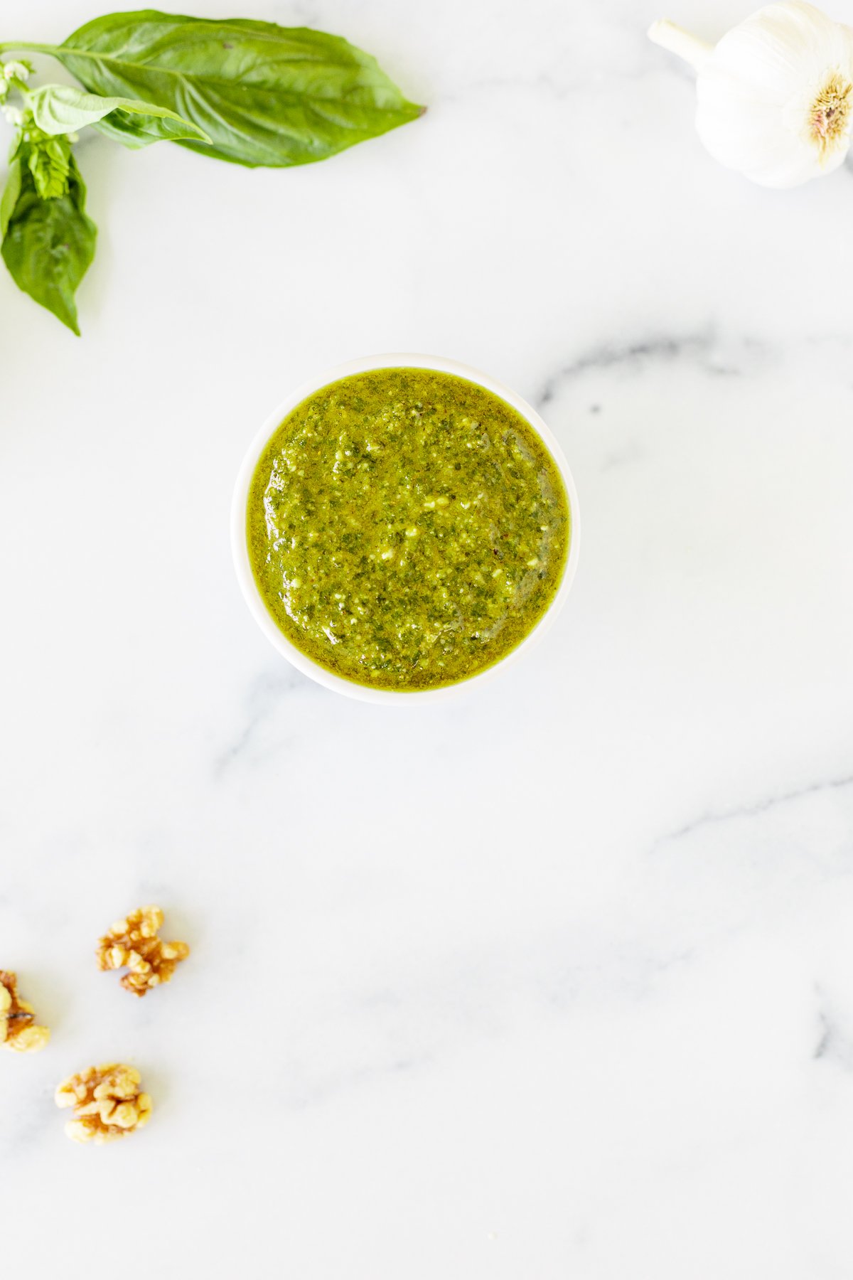 Walnut pesto in a white bowl on a marble countertop.