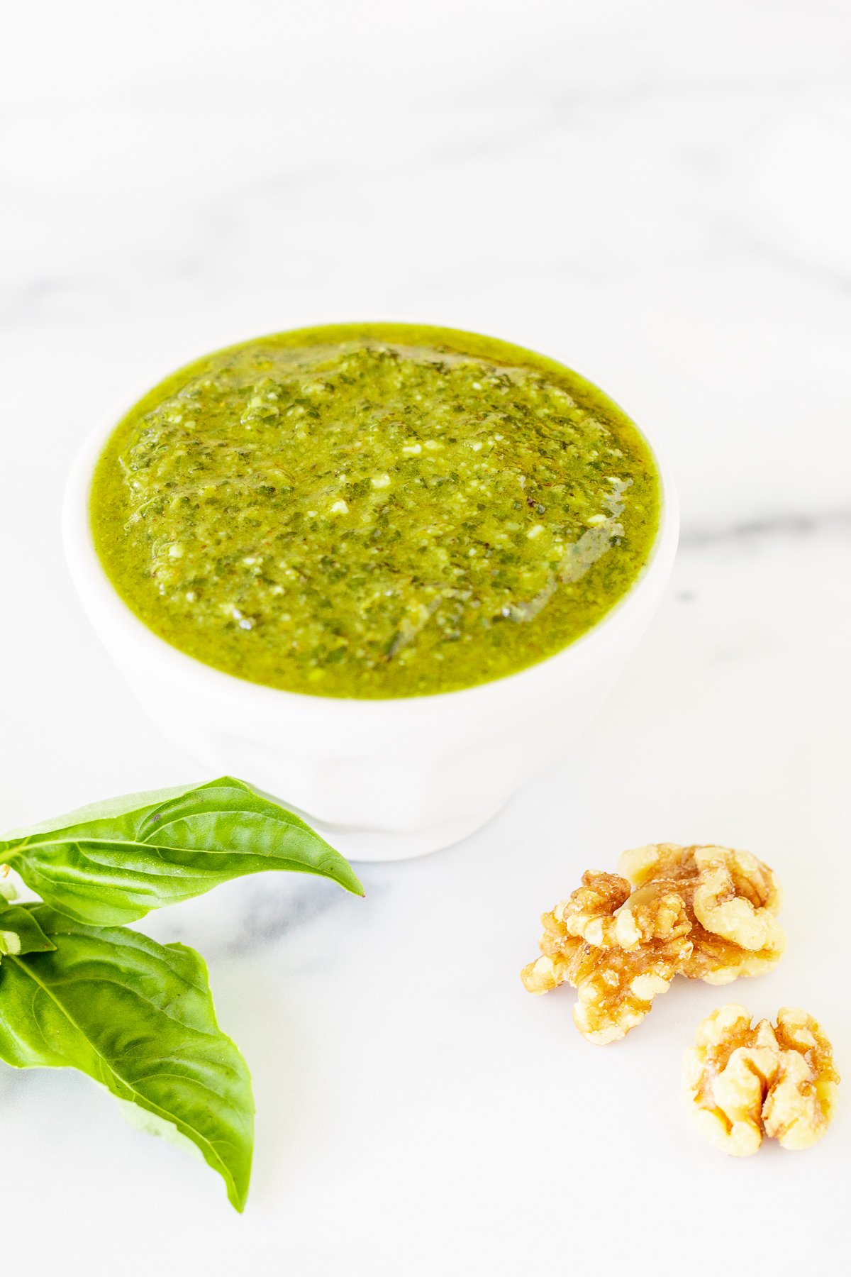 Walnut pesto in a white bowl on a marble countertop.