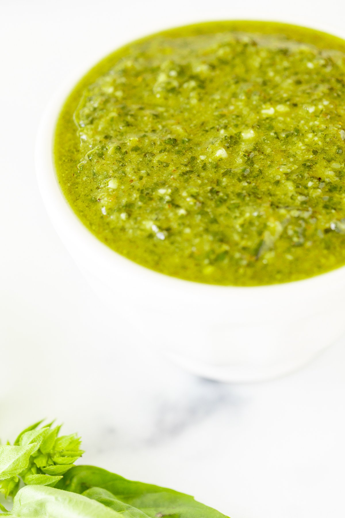 Walnut pesto in a white bowl on a marble countertop.