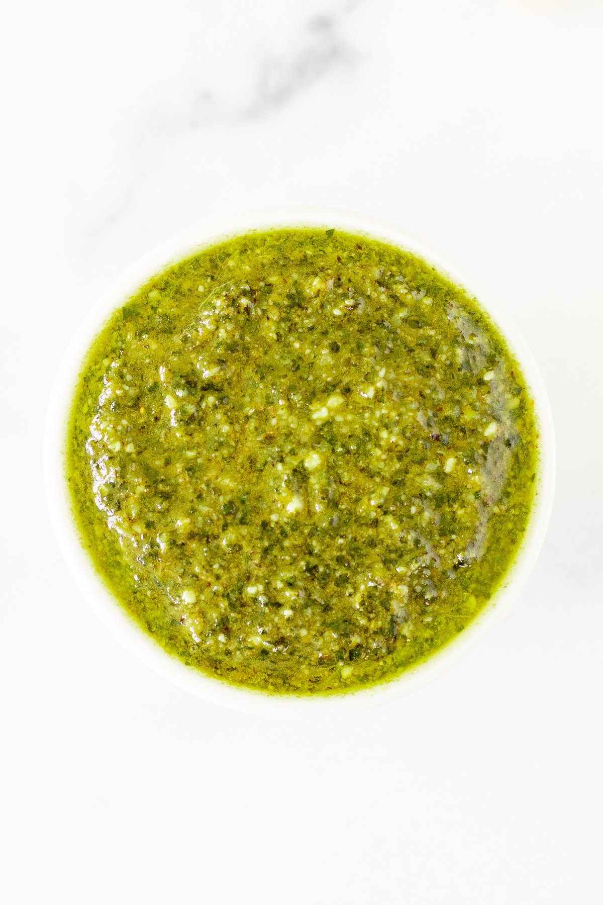 Walnut pesto in a white bowl on a marble countertop.