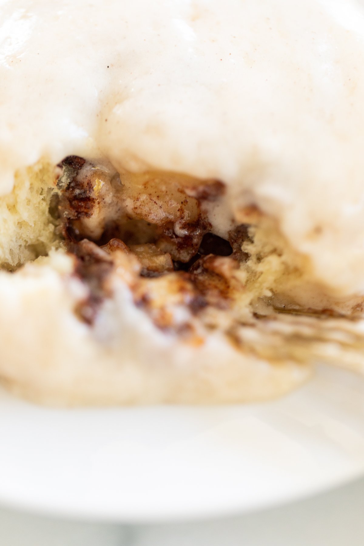 An apple cinnamon roll with icing on it is on a plate.