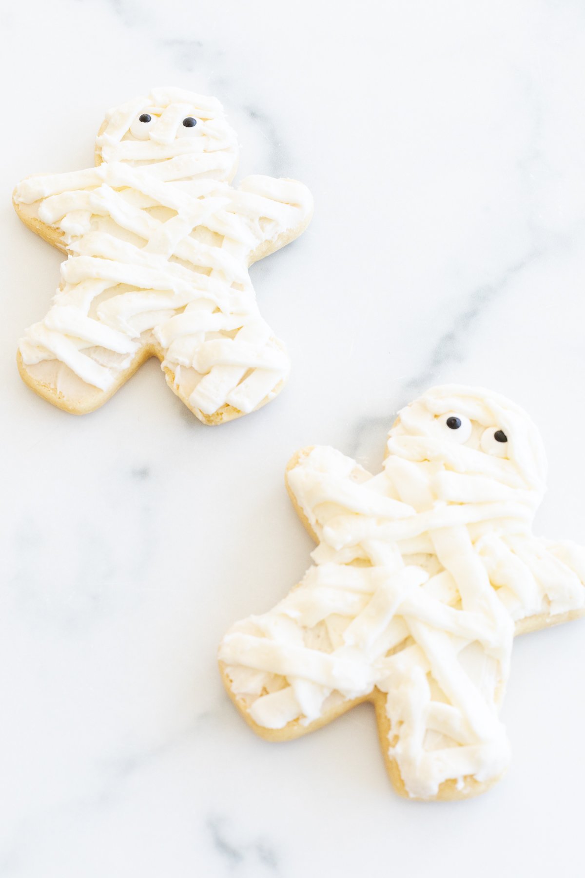 Mummy Halloween sugar cookies laid out on a white surface.