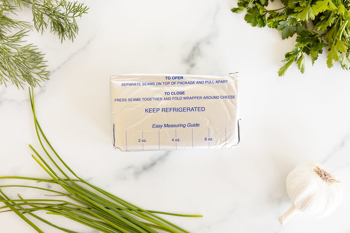 Ingredients for garlic and herb cream cheese on a white countertop.