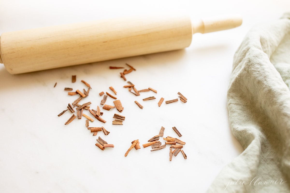 A rolling pin and cinnamon sticks on a marble table.