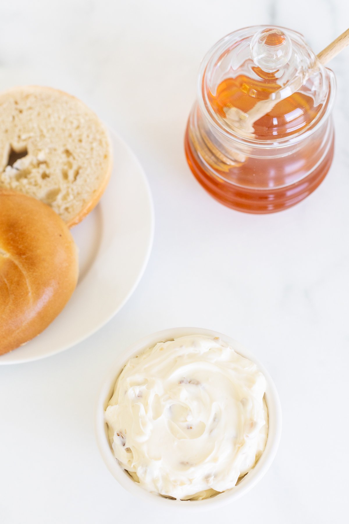 A bagel with Honey Walnut Cream Cheese on a white plate.