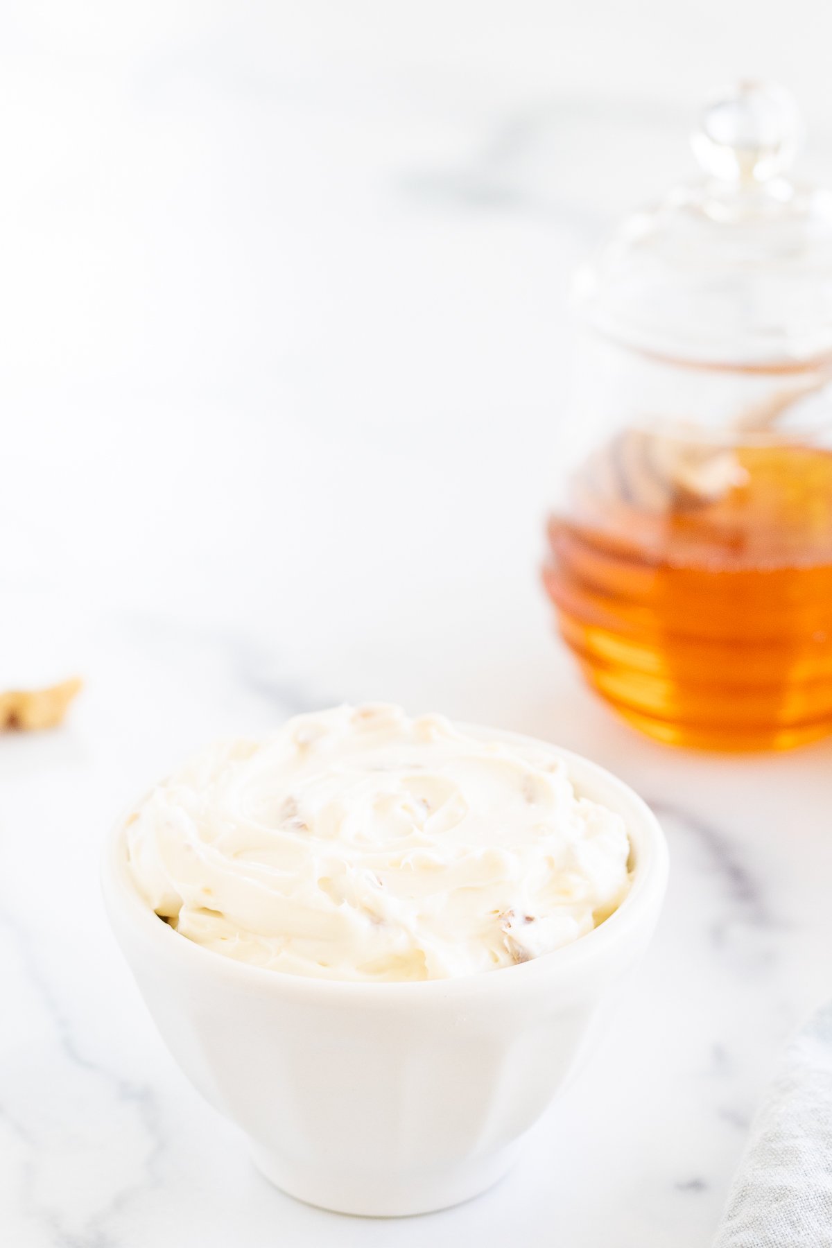 A bowl of honey walnut cream cheese with a jar of honey next to it.