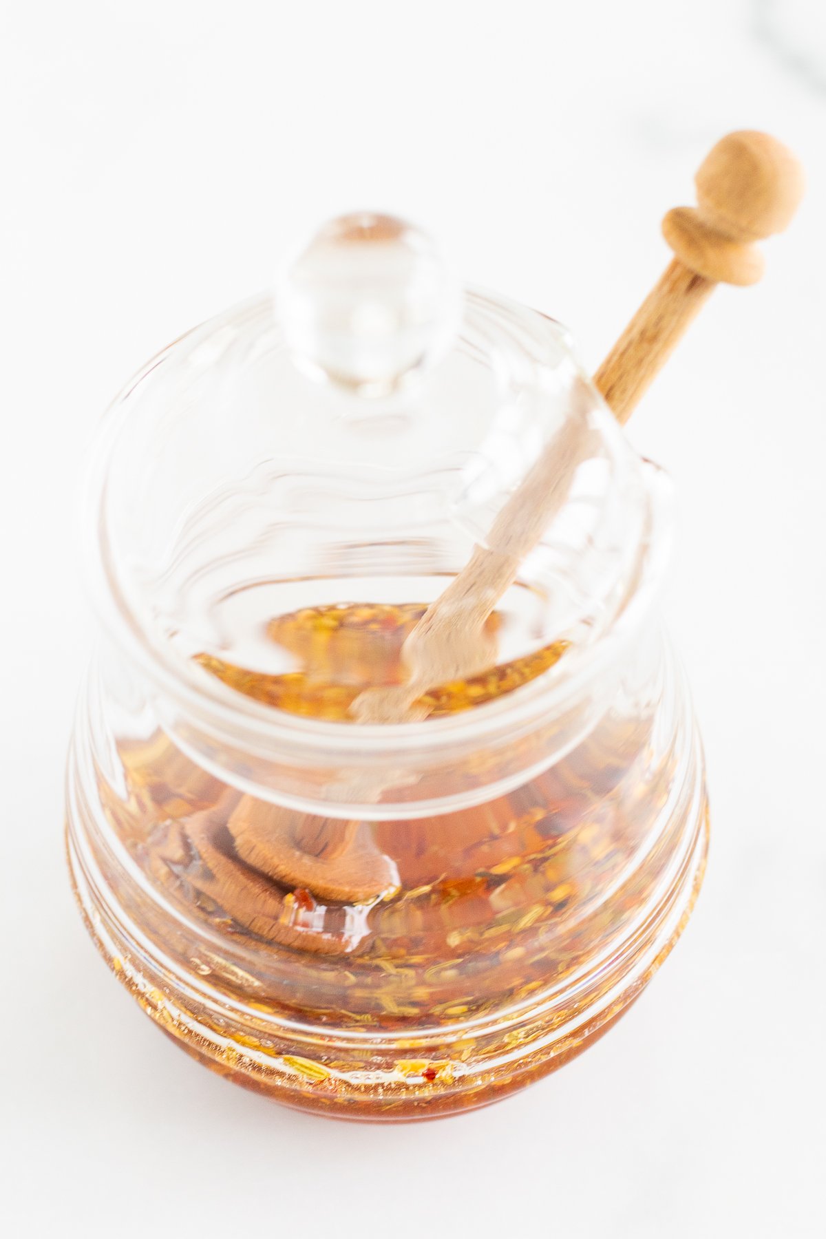 Hot honey in a glass bowl with a wooden spoon.