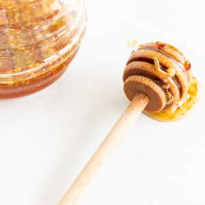 Hot honey with a wooden spoon next to a jar of honey.