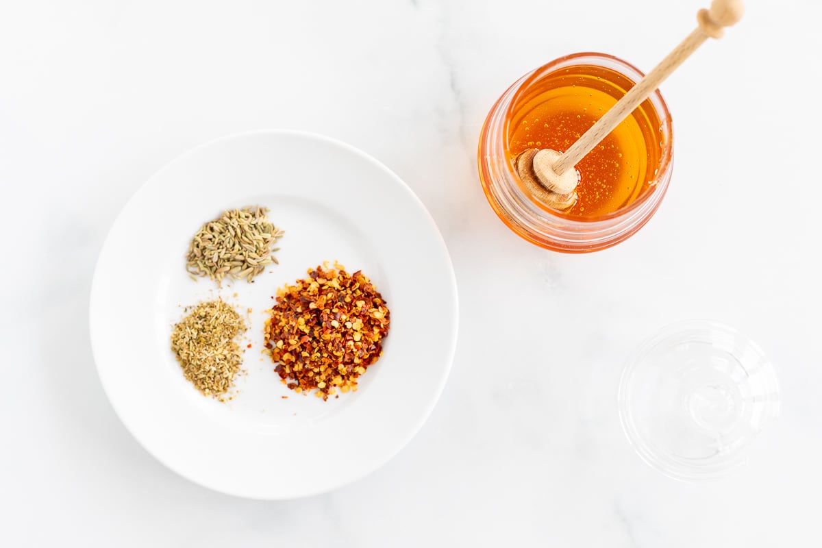 Honey and spices on a white plate.