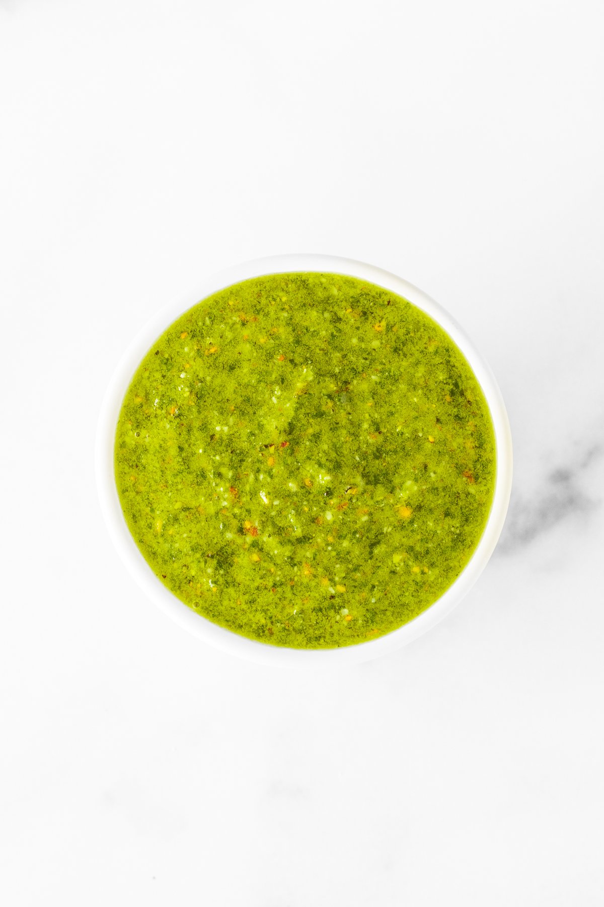 Pistachio pesto sauce in a white bowl.