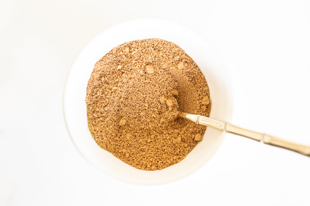 A brown powder in a bowl with a wooden spoon, perfect for making delicious Pumpkin Cinnamon Rolls.