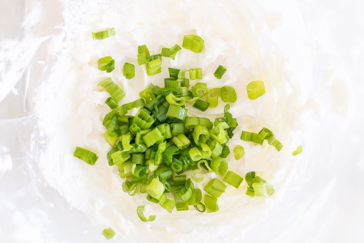 A bowl of cream cheese with green onions (scallion) on top.