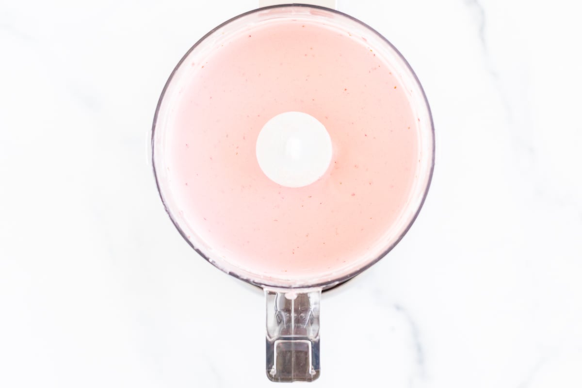 Strawberry cream cheese inside a food processor.