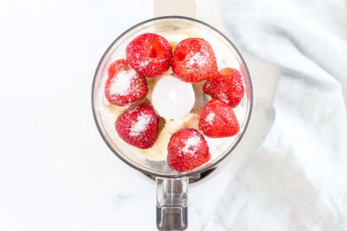 A food processor filled with strawberries and sugar.