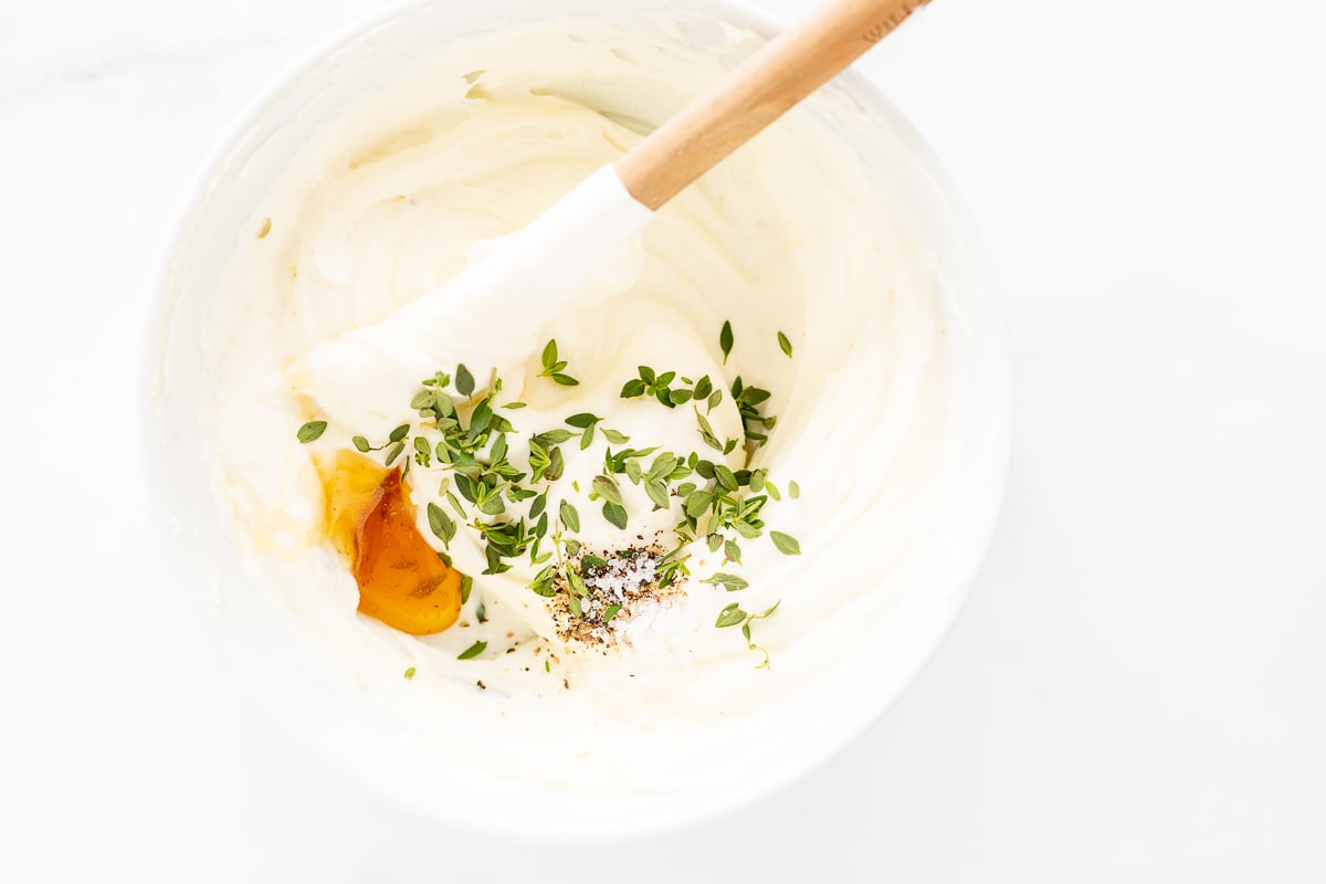 A bowl of whipped ricotta with herbs and a wooden spoon.