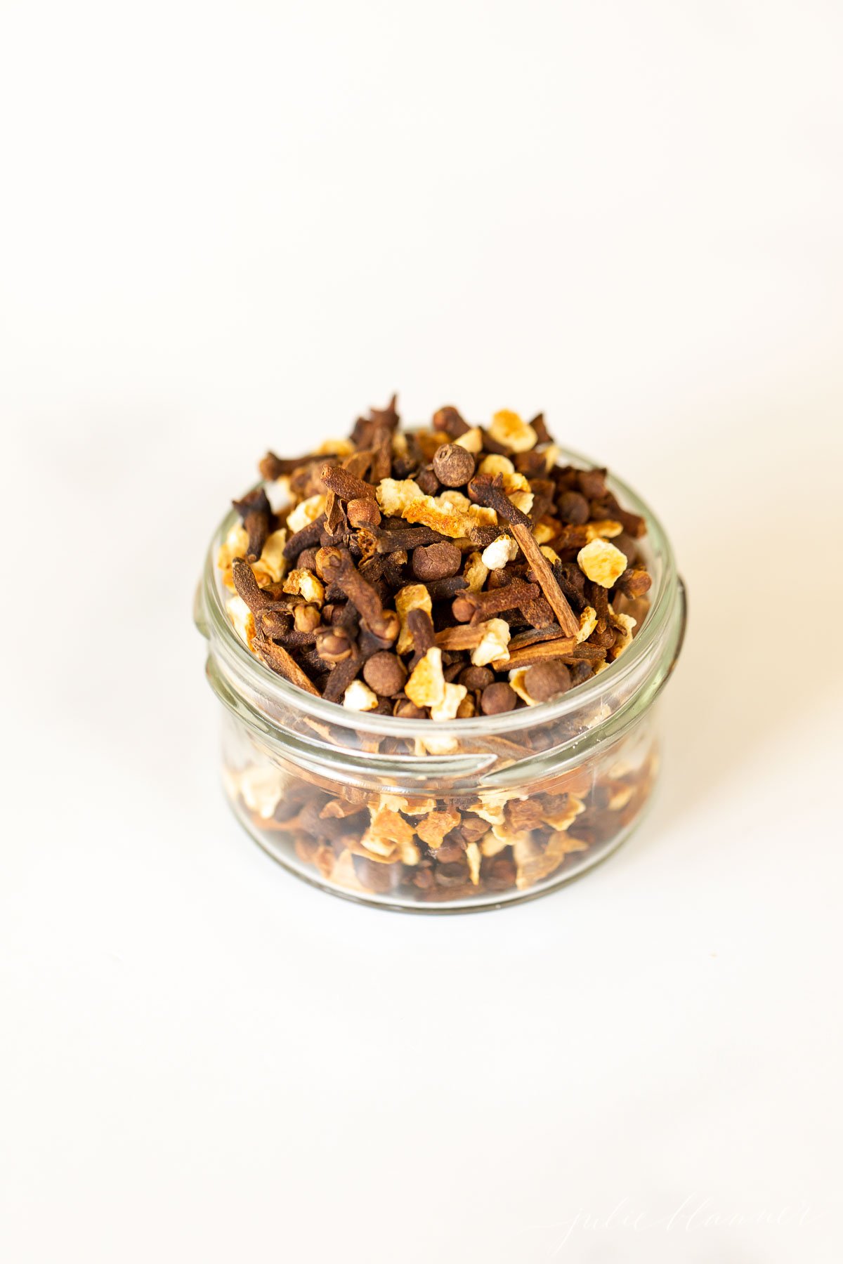 A glass jar filled with cinnamon and other spices, infused with the aroma of mulling spices.
