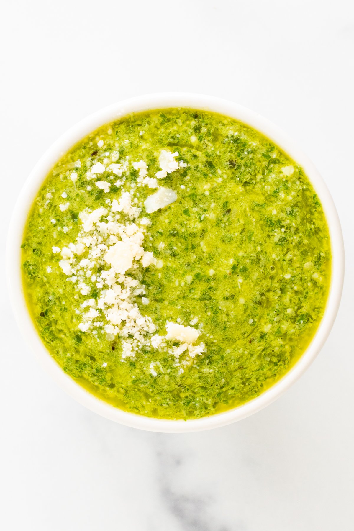 A bowl of green soup with Nut Free Pesto on top.