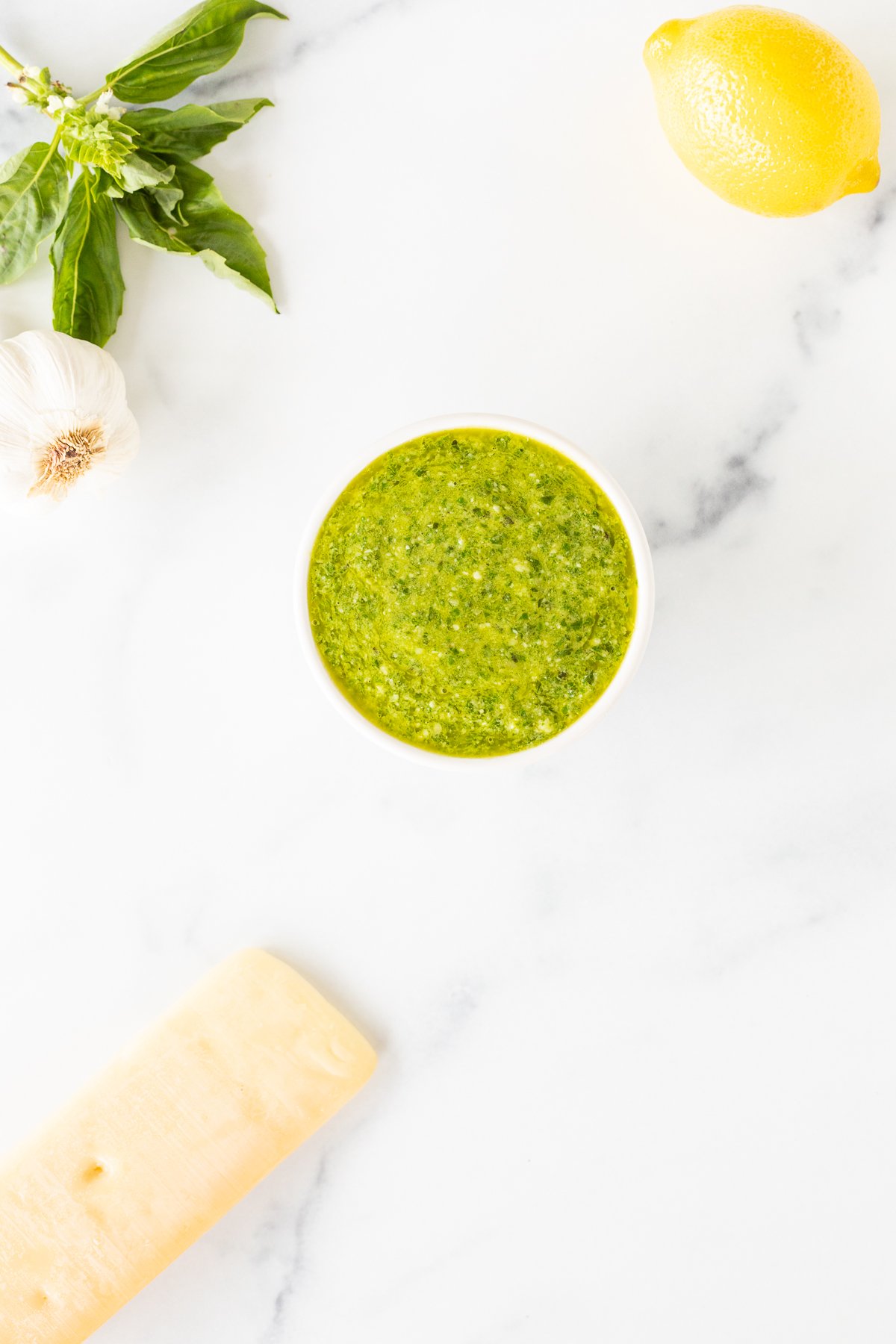 A bowl of nut-free pesto sauce with lemons and garlic.