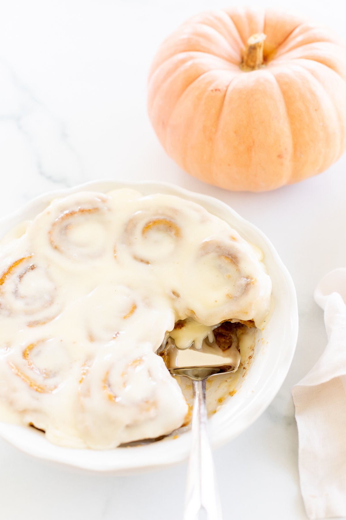 Pumpkin Cinnamon Rolls on a white plate with a fork.