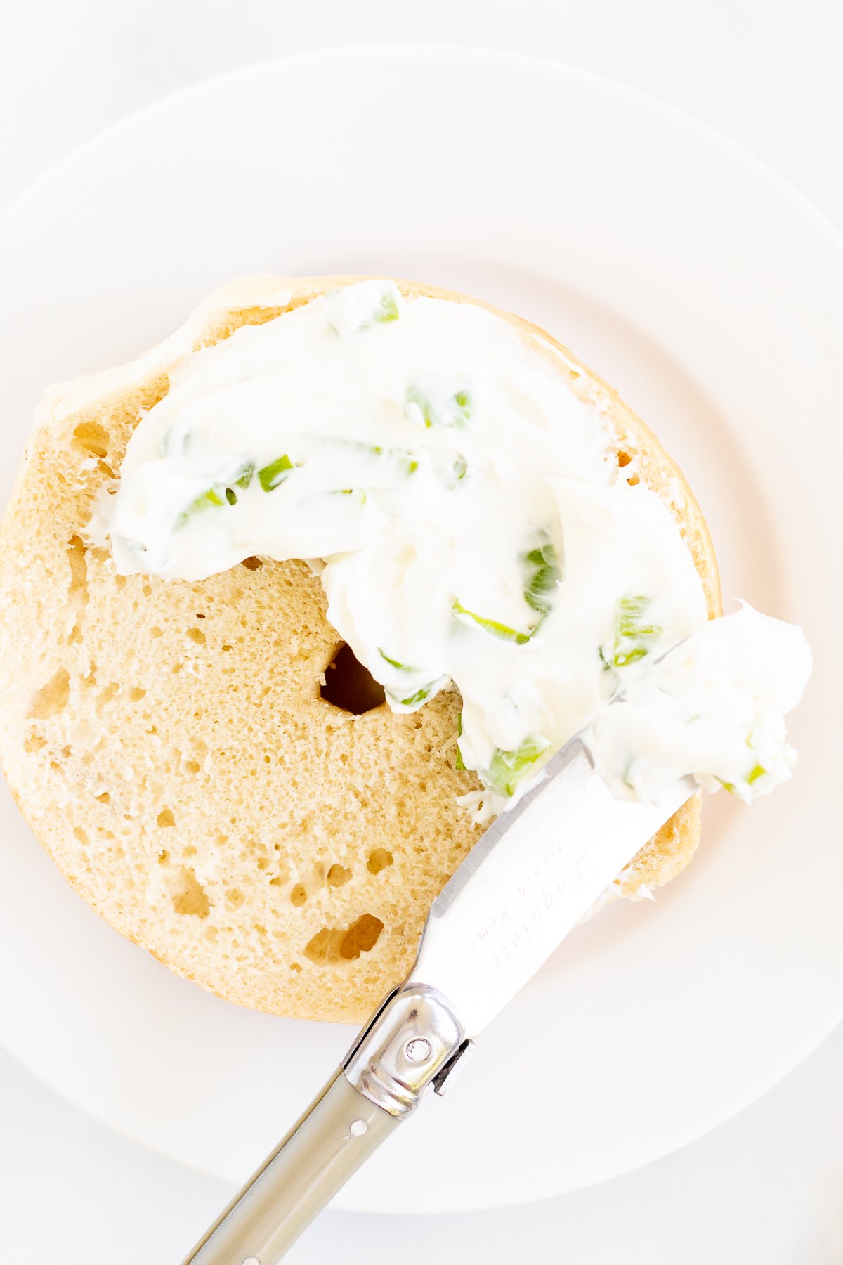 A bagel with scallion cream cheese on it.