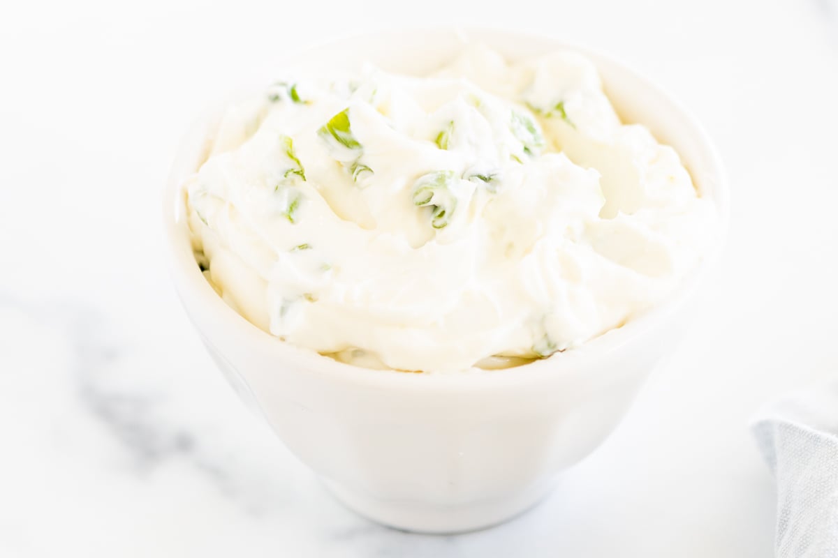 A white bowl with whipped scallion cream cheese.