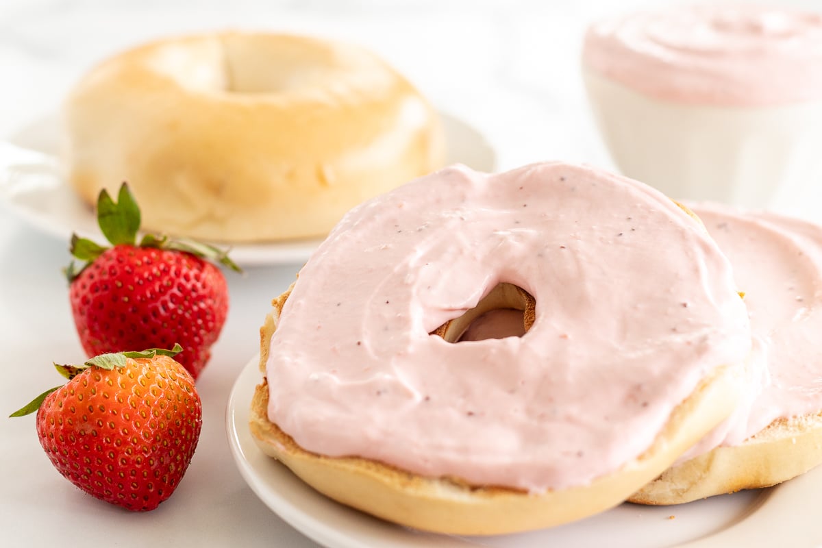 A baguette with strawberry icing and strawberries on it.